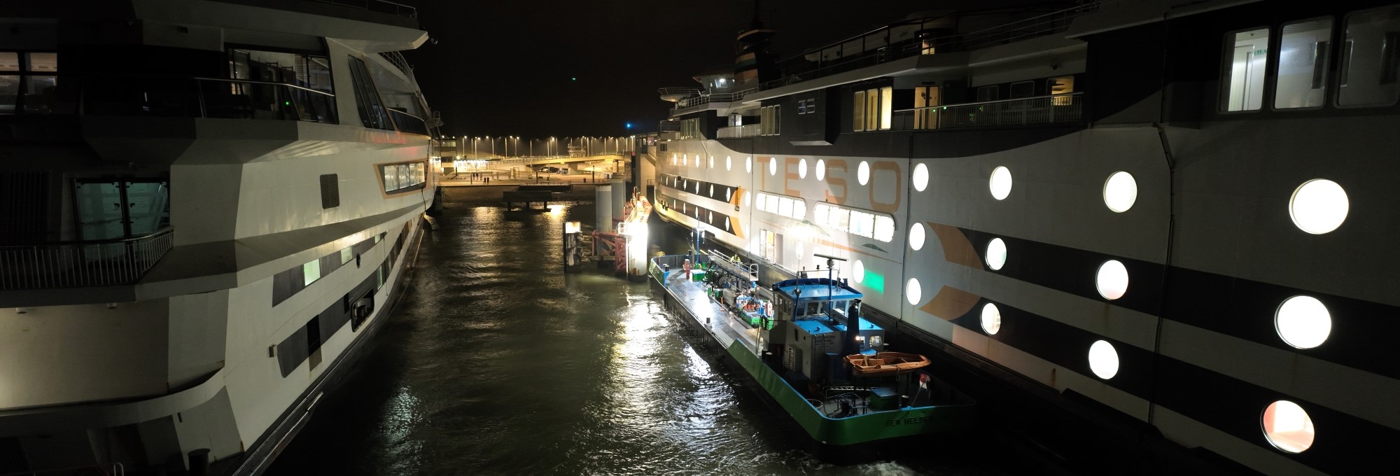 A ferry is seen from the side during a night time ship-to-ship fuel delivery